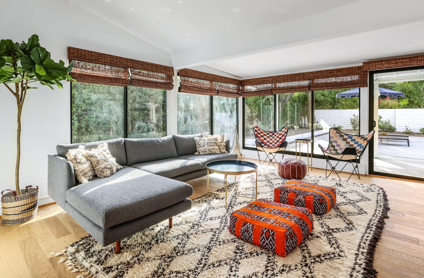 Living room with Moroccan textiles, a gray sectional, and glass doors to the garden